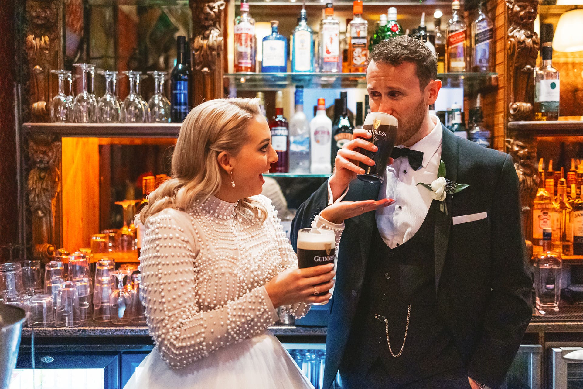 Couple having pint of guinness in the stags head on their wedding day