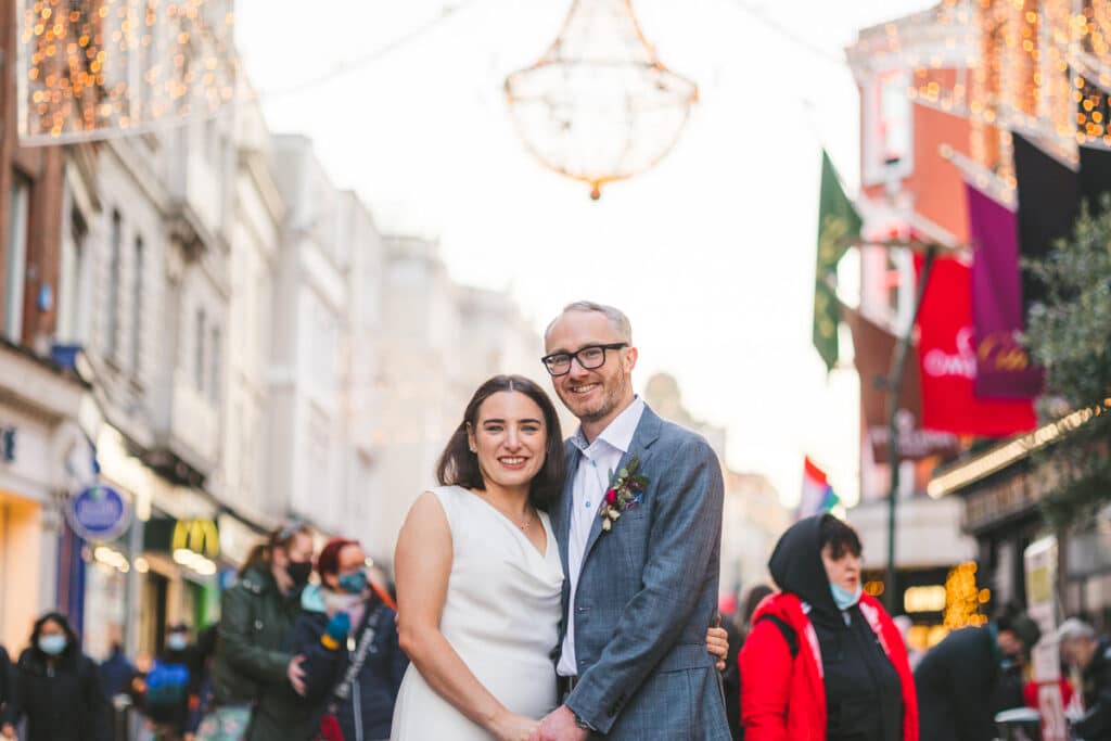 Couple holding hands on Grafton Street on their wedding day Christmas Dublin