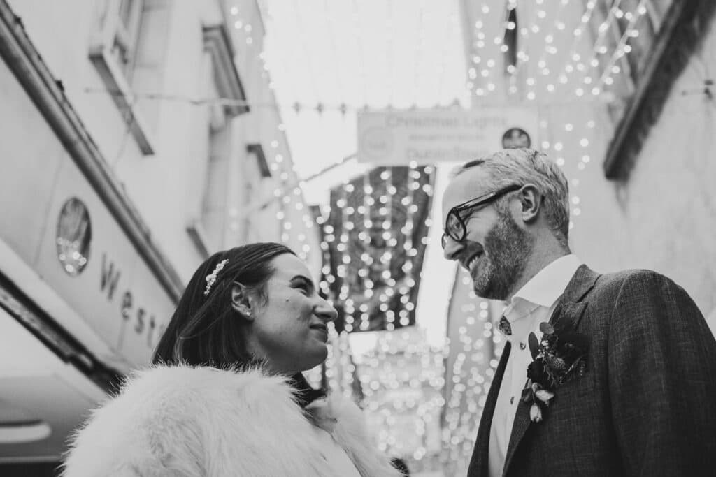 Couple facing each other in front of twinkly lights Dublin city Christmas wedding