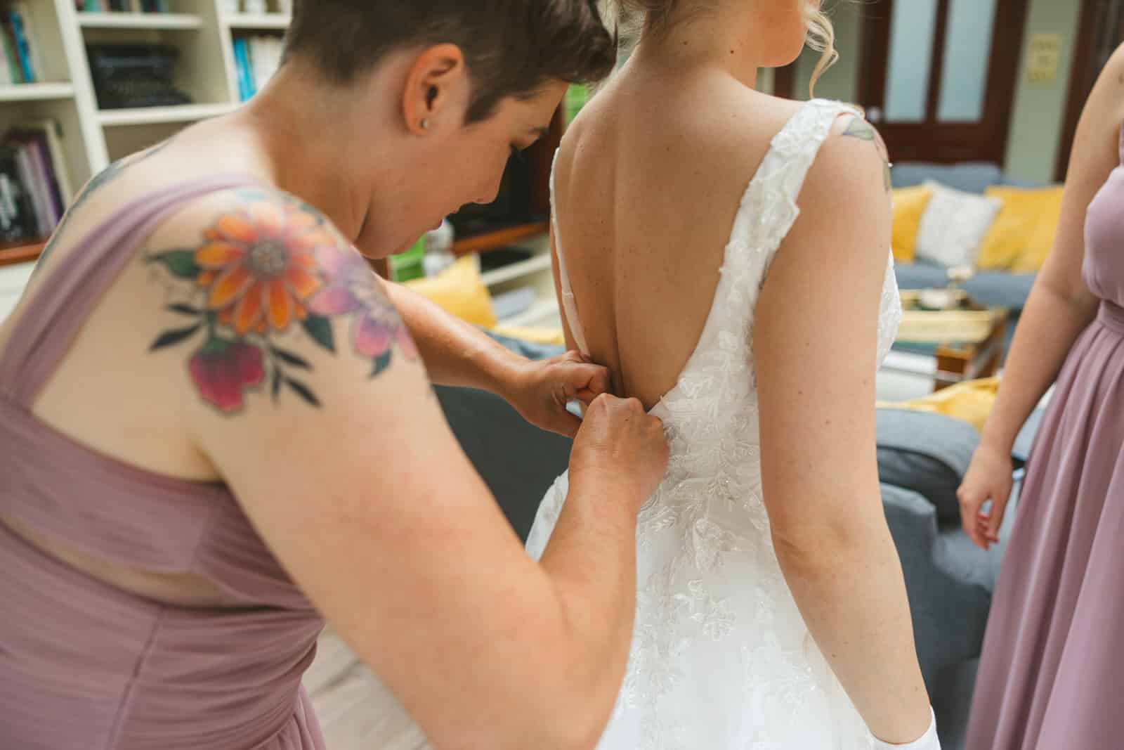 bridesmaid putting bride in to dress